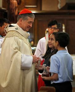 Cardinal Cupich accepts the gifts from Ruby Zabalza and Eric Gallardo during the offertory. (Karen Callaway/ Chicago Catholic)