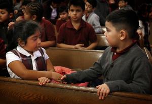 First graders Emily Garcia and Gustavo Guzman from Queen of the Universe School share the sign of peace during Mass. (Karen Callaway/ Chicago Catholic)