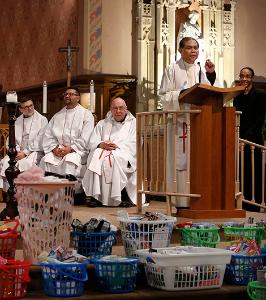Father Salvador Den Hallegado, pastor of St. Nicholas Tolentine Parish, speaks about the students' donation to the Olive Branch Mission, an area homeless shelter. Baskets filled with the donations can be seen on the sanctuary steps. (Karen Callaway/ Chicago Catholic)