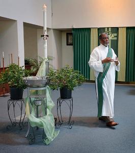Deacon Mervin Johnson takes the holy water to one of the fonts by an entrance at Holy Angels Church. (Karen Callaway/Chicago Catholic)