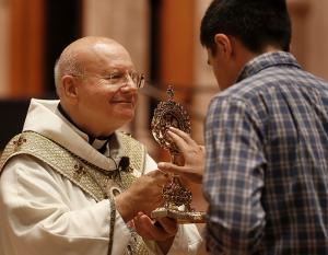 Archbishop Sorrentino holds the reliquary as a man venerates the relics. (Karen Callaway/Chicago Catholic)