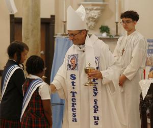 Auxiliary Bishop Mark Bartosic receives the gifts from students from St. Therese Chinese Catholic School. (Karen Callaway/Chicago Catholic)