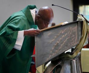 Deacon Michael Foggie kisses the Gospel following the reading. (Karen Callaway/Chicago Catholic)