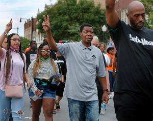 Father Thulani Magwaza, pastor of St. Sabina, holds up his hand in a peace sign during the walk. (Karen Callaway/Chicago Catholic)