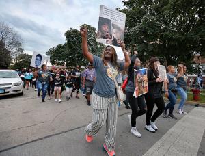 People gesture in response to chants while walking through Auburn-Gresham. (Karen Callaway/Chicago Catholic)