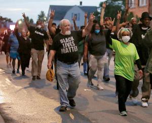 People hold their hands up in a peace sign while walking through Auburn-Gresham. (Karen Callaway/Chicago Catholic)