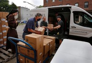Alexian Brother Tom Klein loads a van with 50 boxes of food that will be delivered to those in need that can't travel  to the pantry at the mission. (Karen Callaway/Chicago Catholic)