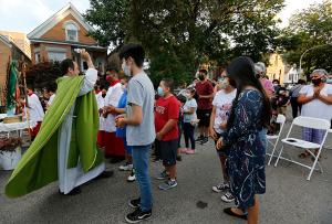Father Marulanda sprinkles holy water over children and youth following a blessing from the congregation at the end of Mass. The blessing is a tradition during street Masses in Latino parishes. (Karen Callaway/Chicago Catholic)