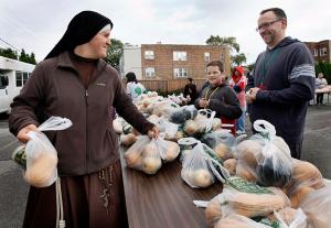 Franciscan Sister of the Eucharist Kate O’Leary distributes food during the monthly food give-away at Our Lady of the Angels Mission on Oct. 3, 2015. The mission operates a food pantry and various outreach efforts in the West Humboldt Park neighborhood, which often sees incidents of violence. For more, visit missionola.com. (Karen Callaway/Chicago Catholic)
