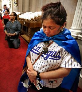 A woman dressed in a Nicaragua baseball jersey and blue cape prays during Mass. (Karen Callaway/Chicago Catholic)