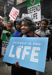 A
woman holds a
sign as she walks
through downtown
Chicago. (Karen Callaway / Catholic New World)