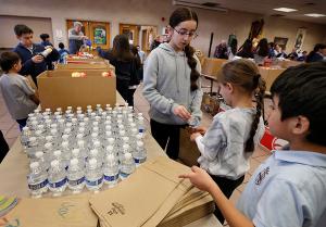 Sixth grader Alani Aguilar helps first graders Marie Bulski and Nicholas Sanchez pack lunches. (Karen Callaway/Chicago Catholic)