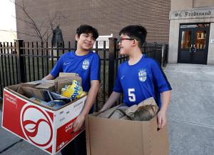 Fifth graders Jacob Garcia and Max Trudgen carry boxes of food to a van after they and fellow students packed lunches. (Karen Callaway/Chicago Catholic)