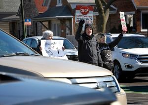 Members of the Sisters and Brothers of Immigrants hold up signs to show people passing by in cars. (Karen Callaway/Chicago Catholic)