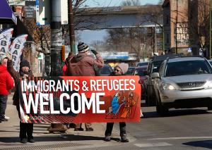 Members of the Sisters and Brothers of Immigrants hold up signs to show people passing by in cars. (Karen Callaway/Chicago Catholic)