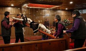 Mauro Cisneros, Doroteo Cisneros, Martin Carillo and Martin Abrejo secure the statue inside the glass case in the new chapel. (Karen Callaway/Chicago Catholic)