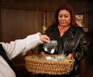 Ma Amparo Sanchez hands out cotton balls that have touched the statue for parishioners to take home. (Karen Callaway/Chicago Catholic)