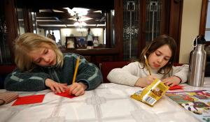 First communicants Meg Nondorf and Ana Contero decorate cards and write messages of encouragement that will be placed in the lunch bags. (Karen Callaway/Chicago Catholic)