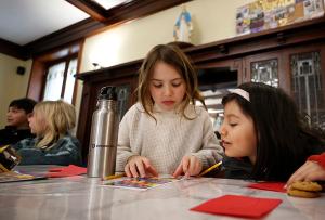 First communicants Benjamin Mejias, Ava Kolaczynski, Meg Nondorf and Ana Contero decorate cards and write messages of encouragement that will be placed in the lunch bags. (Karen Callaway/Chicago Catholic)