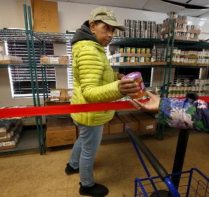 Barbara Newby shows clients what’s available on the soup and dip shelves. (Karen Callaway/Chicago Catholic)
