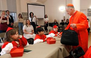 Cardinal Cupich passes out small crucifixes that are replicas of that on the crosier used by Pope Leo XIV. The cardinal brought the crucifixes back from his recent visit to Rome. (Karen Callaway/Chicago Catholic)