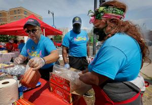 Annette Nance-Holt, co-founder of Purpose Over Pain and commissioner of the Chicago Fire Department, and Alicia Hudson-Idleburg cook hamburgers and hotdogs for passersby on the corner of 79th Street and Racine Avenue during St. Sabina Parish’s  Annual Day of Service on July 31, 2021. Darryl Johnson (center) worked the grill. (Karen Callaway/Chicago Catholic)