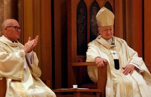 Cardinal Cupich smiles in response to receiving a standing ovation from the congregation. Deacon David Keene, archdiocesan chancellor, left, joins in the round of applause. (Karen Callaway/Chicago Catholic