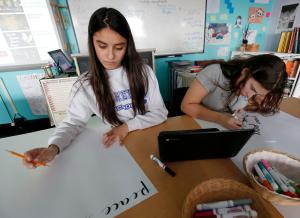 Denae Cervantes y Leilani Delvalle, estudiantes de octavo grado en la escuela católica St. Helen, crearon avisos sobre la paz el 13 de marzo para exhibir en la escuela e iglesia al día siguiente. Foto: Karen Callaway