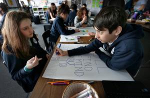 Sophia Marshek y Zain Javan, alumnos de séptimo grado de la escuela St Helen trabajan en sus pancartas el 13 de marzo. Foto: Karen Callaway