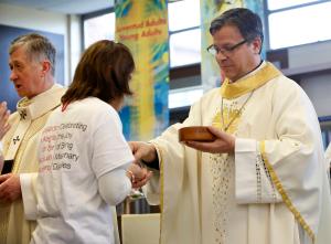 El obispo Alberto Rojas distribuye la comunión mientras el cardenal Blase J. Cupich, arzobispo de Chicago, fue el celebrante principal en una misa en español en honor a los participantes parroquiales del Encuentro pastoral arquidiocesano en DePaul College Prep. en preparación para el V Encuentro nacional.  Después del rito de cierre, el cardenal comisionó a los participantes a ir y compartir la Buena Nueva de Cristo Resucitado. Foto: Karen Callaway/Católico