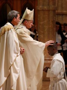 El cardenal Cupich impone sus manos sobre Patrick Kizza. Los ordenados tienen un rango de edad de 28 a 38 años y provienen del área de Chicago y Michigan, así como también México, Uganda y Vietnam. Foto: Karen Callaway/Católico.