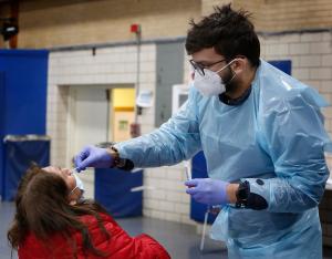 Pruebas de detección de Covid-19 en Sta. Inés: Sanu Amin, de Prism Health Lab, administra una prueba de detección de Covid-19 a María Pérez, parroquiana, en el gimnasio de la escuela Sta. Inés de Bohemia, en La Villita, el 30 de enero. María se hizo la prueba porque estuvo expuesta en su trabajo como babysitter. Foto: Karen Callaway/Católico