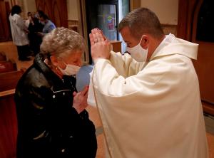 El recién ordenado Ryand Brady da su primera bendición a Joan Lewis, quien le dio su cáliz bendecido por el papa Benedicto.  Foto: Karen Callaway/Católico