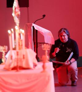 Jesús “Chuy” de León, director ejecutivo del grupo juvenil, se arrodilla durante la adoración en la celebración “Fired Up Fridays” en febrero de 2024.