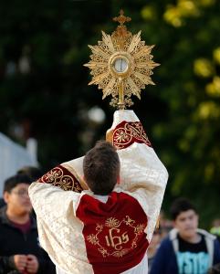 El padre Tom Boharic, pastor de Madre de las Américas levanta la custodia hacia los jóvenes durante la procesión de septiembre de 2025.