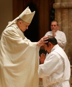 El cardenal Cupich posa sus manos sobre el candidato Galdino Hernandez Ramirez.