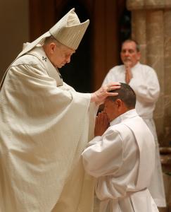 El cardenal Cupich posa sus manos sobre el candidato J. Hugo Arellano Ibarra.