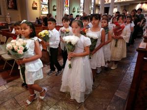 Niños avanzan en procesión al altar con flores para Santa Ana.