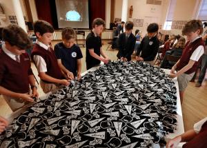 Alumnos atan las orillas de la manta de Chicago White Sox que le enviaron al papa León. Fotos: Karen Callaway/Católico