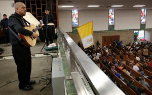 Benny Ríos, director del coro, mira hacia la congregación en San Beda.
