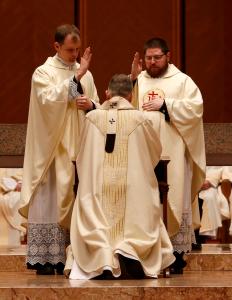 Los sacerdotes recién ordenados, el canónigo Joseph Brom y el padre Colm Mitchell, dan su primera bendición al cardenal al final de la misa.