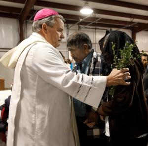 El obispo Manz bendice a Francisco Martínez y su esposa después de misa en un granero donde los jornaleros pizcan tomates, en Alabama, el 24 de octubre de 2013. Foto: Karen Callaway/Católico