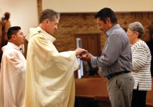 El padre Juan Pablo Avila Ibarra y el arzobispo Cupich distribuyen la comunión en la misa que celebró el 175 aniversario de la parroquia de Transfiguración en Wauconda, el 6 de agosto. Foto: Karen Callaway/Católico