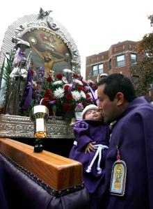 Edward Henríquez da un beso a su hija, Sara, de dos meses durante la procesión del Señor de los Milagros en St. Ignatius, en octubre de 2008.