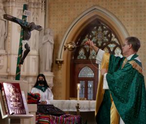 El padre Steven Bauer inciensa la estatua del Cristo Negro en la celebración del 15 de enero.