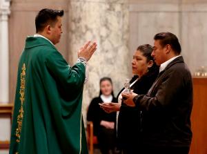 El padre Erick Díaz recibe los dones durante la misa del 19 de febrero.