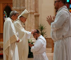 El cardenal Cupich deposita sus manos sobre el recién ordenado padre Jesús Raya Custodio.