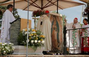 El cardenal Cupich sostiene un extremo mientras el cardenal Aguiar Retes presenta una réplica de la imagen de Ntra. Sra. de Guadalupe.