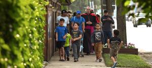 El obispo Kevin Birmingham encabeza a un grupo de migrantes por Irving Park Road el 18 de junio para asistir a la misa en la iglesia St. Pascal, en Chicago. Parroquianos de Ntra. Sra. del Rosario invitaron a migrantes que se quedan en vivienda temporal en Wilbur Wright College, cerca de allí, a la misa de 6:00 p.m. seguida de una cena. Lea la historia en catolicoperiodico.com. Foto: Karie Angell Luc/Católico