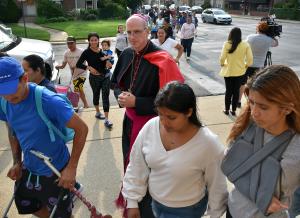 El obispo Kevin Birmingham guía a la gente hacia la entrada de St. Pascal.